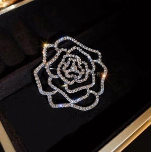 Détail de la broche camélia argentée avec des strass étincelants et un design ajouré