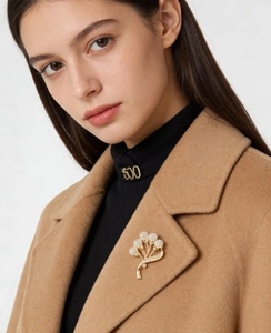 Détail d'une broche bouquet de fleurs dorées avec cristaux blancs sur un manteau en laine