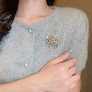 Exquise broche rose évidée avec cristaux étincelants sur un pull bleu en détail