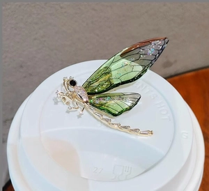 Macro detail of elegant dragonfly brooch with green wings and white zircon inlay