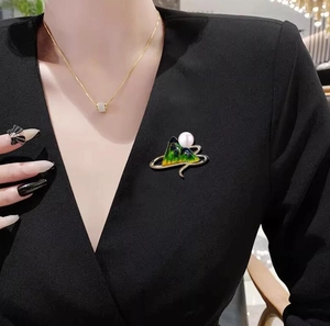 Detail of green enamel mountain brooch with pearl on a black suit jacket for women