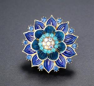 Macro detail of enamel lotus flower brooch featuring blue rhinestones and gold plating