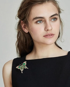 Close-up of luxury butterfly brooch with emerald stones and crystals on black fabric