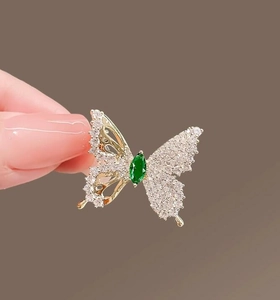 Detailed macro view of butterfly brooch with sparkling crystals and a green center stone