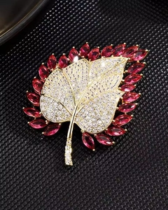 Macro shot of gold leaf brooch with white zircons and red marquise-cut gems