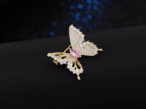 Macro shot of butterfly brooch with pink marquise gemstone and sparkling zircons