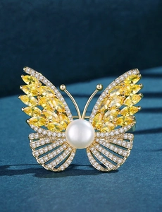 Macro detail of luxury butterfly brooch with yellow marquise gems and central pearl