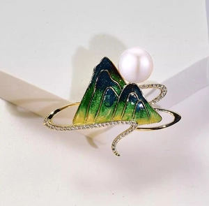Macro detail of enamel landscape brooch featuring a large pearl and sparkling crystals