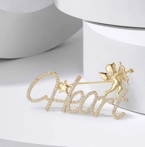 Detailed close-up of golden Heart brooch with Cupid design and sparkling rhinestones