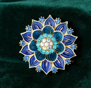 Macro shot of blue gradient enamel lotus brooch with sparkling crystals on green velvet