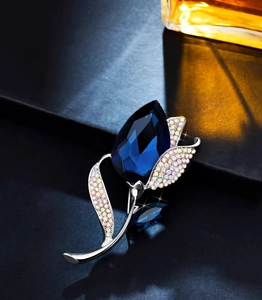Macro detail of tulip crystal brooch featuring deep blue faceted stone and pave petals