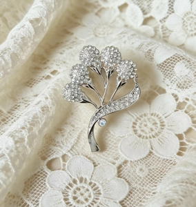 Gros plan détaillé d'une broche fleurie argentée ornée de strass et d'une perle opale