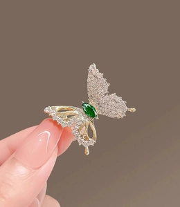 Macro detail of butterfly brooch with white diamonds and marquise green gemstone
