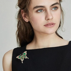 Elegant gold butterfly brooch with emerald green gemstones and sparkling white zircons