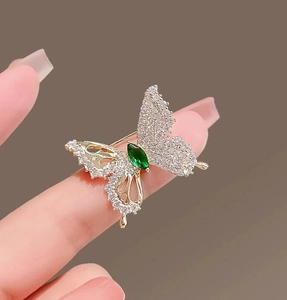 Detailed close-up of butterfly brooch with sparkling crystals and green gemstone