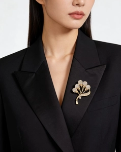 Détail d'une broche fleur dorée avec cristaux blancs sur une veste de costume noir