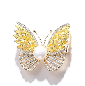 Elegant gold butterfly brooch with yellow gemstones and a large pearl centerpiece