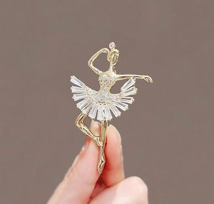 Détail d'une élégante broche ballerine avec cristaux scintillants, tenue en main pour échelle