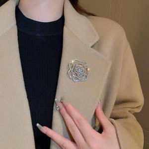 Vue détaillée de la broche rose argentée évidée sertie de cristaux sur revers de manteau