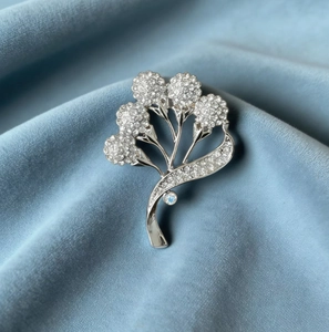 Détails macro d'une broche fleur argentée avec strass blancs sur velours bleu