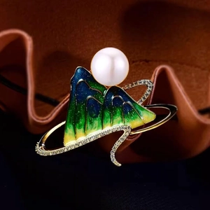 Detail of green enamel mountain brooch with white pearl and sparkling diamond accents