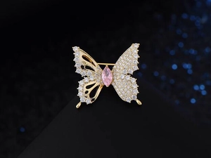 Detailed macro view of a golden butterfly brooch with pink gemstone and white zircon stones