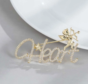 Close-up of golden Heart brooch with Cupid and stars, inlaid with sparkling crystals