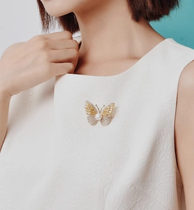 Detailed view of luxury butterfly brooch with yellow crystals and pearl on a white dress