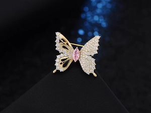 Macro shot of butterfly brooch with sparkling zircons and pink stone on a black stand
