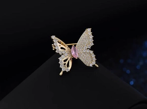 Macro view of butterfly brooch with pink marquise stone and gold hollow wings