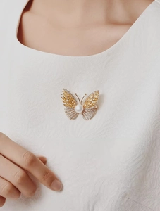 Detailed close-up of a luxury butterfly brooch with yellow crystals and white pearl