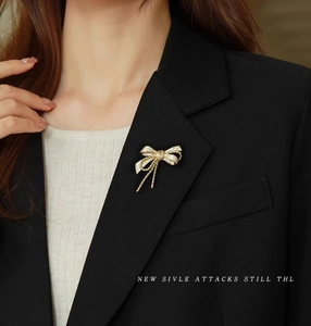Elegant gold bowknot brooch with zircon inlay and tassels on a black suit lapel