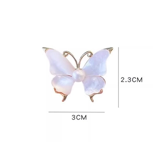 Detail shot of vintage butterfly brooch with dimensions 3cm by 2.3cm and pearl center