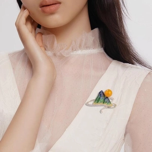 Elegant enamel landscape brooch with green mountain design and pearl accent on model