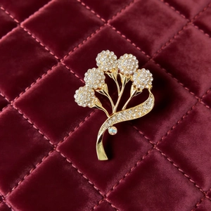 Élégante broche bouquet de fleurs dorées avec strass blancs sur velours rouge