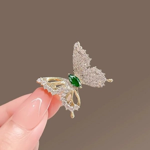 Elegant hollow butterfly brooch with sparkling crystals and emerald green stone in hand