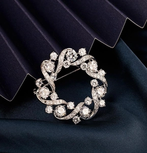 Detailed close-up of a silver floral wreath brooch set with sparkling crystals and gems