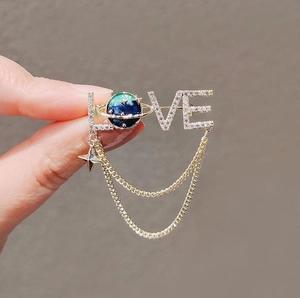 Macro shot of LOVE brooch with tassel chains and starry galaxy planet detail