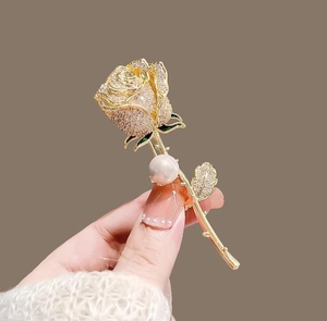 Détail d'une élégante broche rose dorée avec strass en cristal et une grande perle ronde