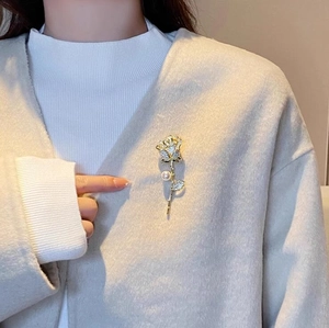 Élégante broche rose dorée avec cristaux et perle blanche sur un manteau en laine beige