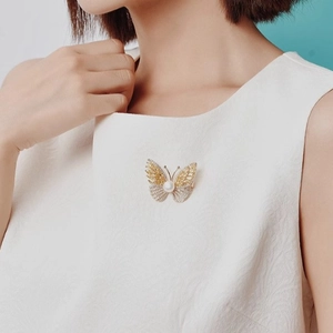 Luxurious butterfly brooch with zircons and pearl worn on a white dress by a model