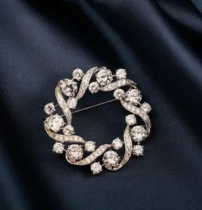 Detailed close-up of a silver circular wreath brooch with sparkling cubic zirconia on blue silk