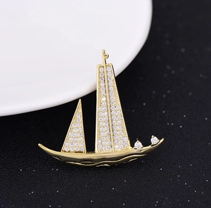 Vue détaillée d'une broche voilier dorée avec cristaux zircons sur fond noir chic