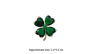 Macro detail of a gold four-leaf clover brooch with emerald crystals and size measurements