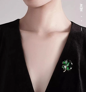 Detail of four-leaf clover brooch with emerald green crystals on black velvet outfit