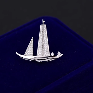 Broche voilier raffinée sertie de zircons cubiques sur un écrin en velours bleu