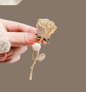 Détail de broche rose avec cristaux pavés, feuille émaillée verte et perle