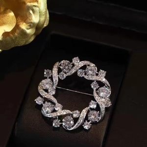 Elegant silver round wreath brooch with sparkling clear stones on black jewelry box
