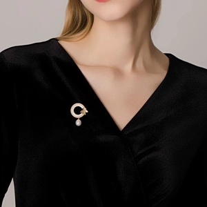 Broche papillon dorée avec cercle en zircon et perle sur manteau en velours noir