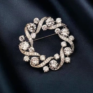 Elegant silver round wreath brooch pin with sparkling white zircon stones on silk fabric